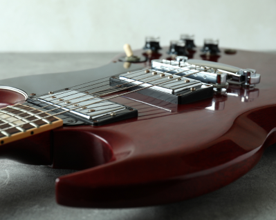 red-electric-guitar-on-gray-textured-table-2021-09-14-17-46-36-utc 1